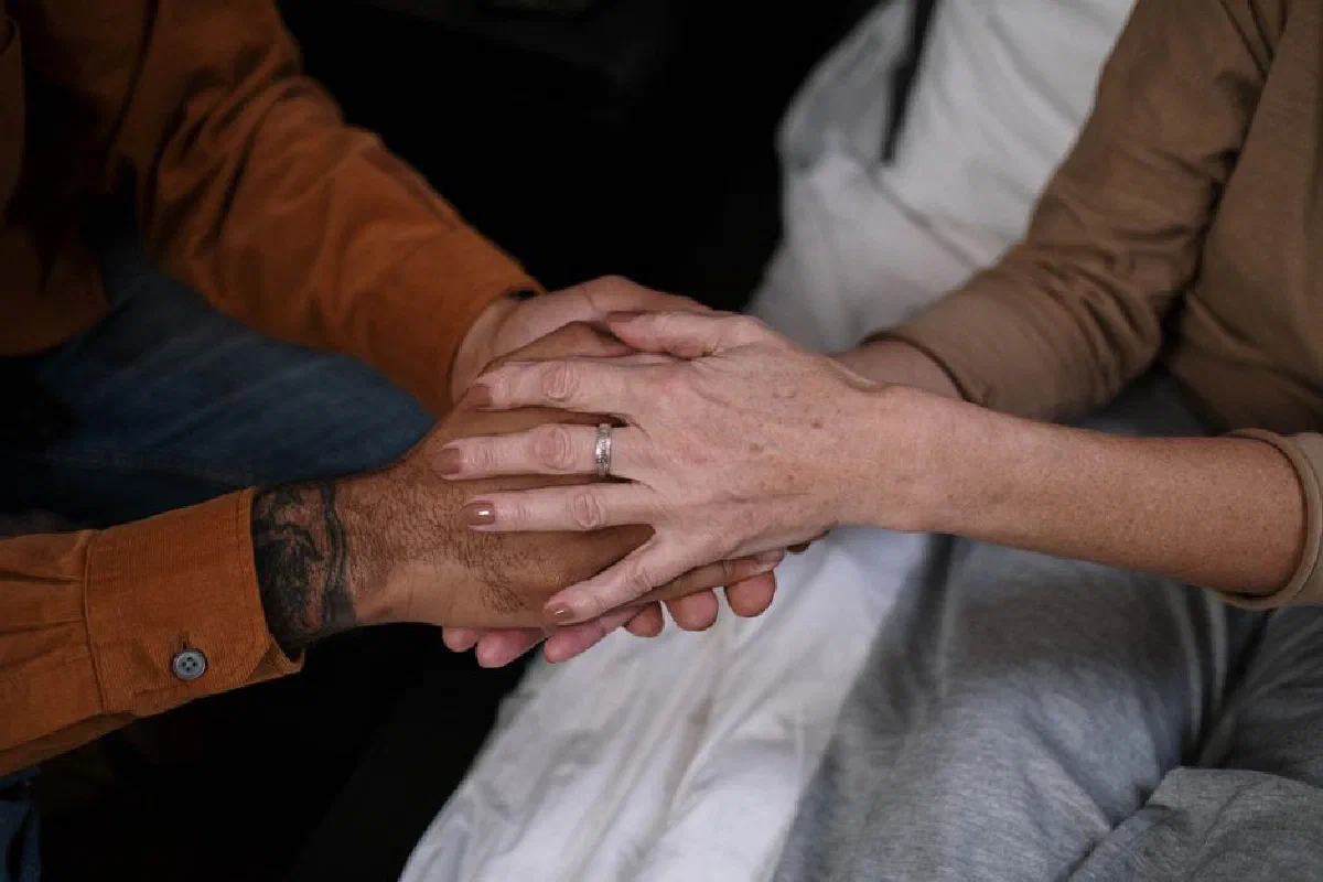 Close-up of two people holding hands, symbolizing love and companionship.