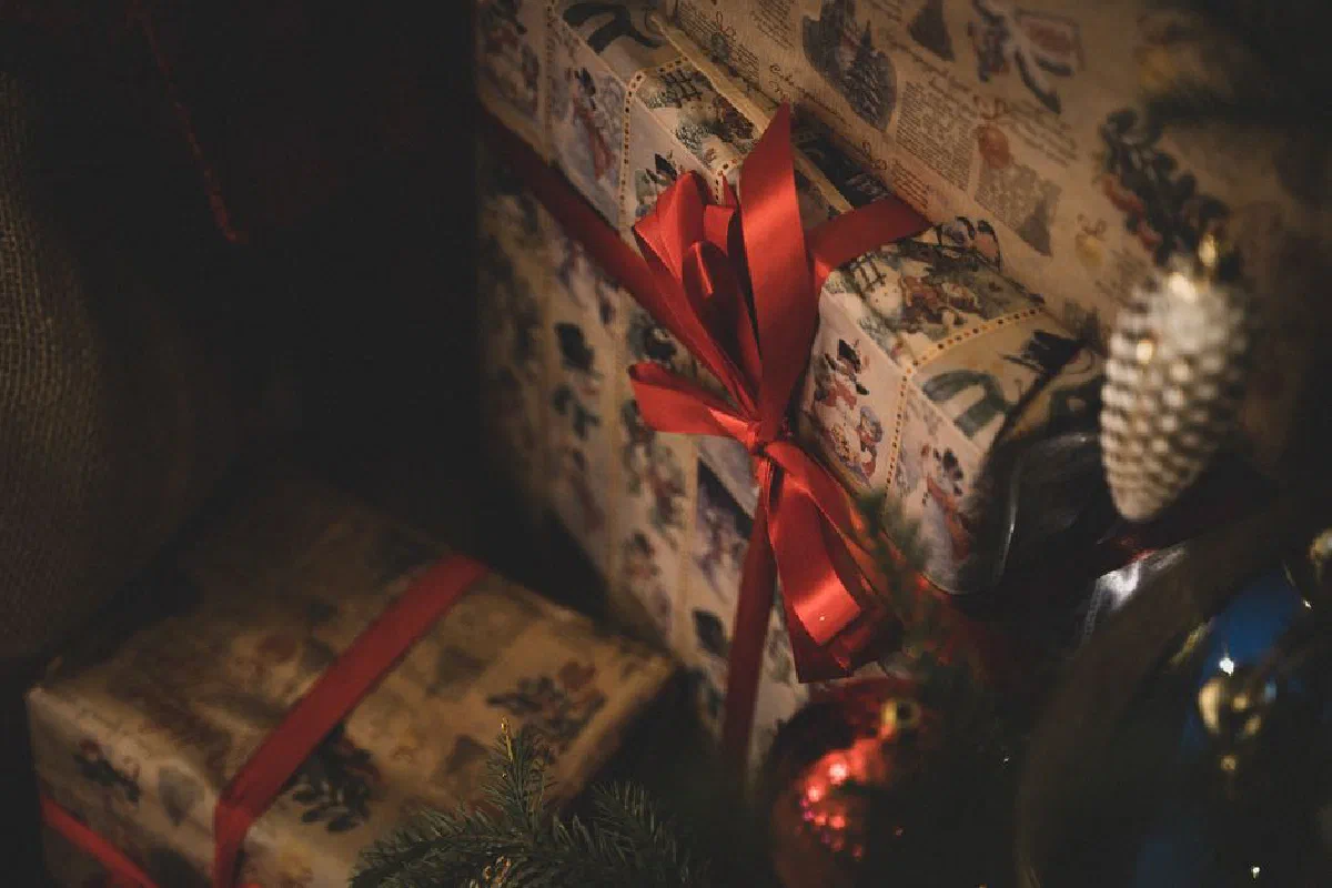 Beautifully wrapped Christmas gifts with red ribbons beside a decorated tree, perfect for holiday celebrations.