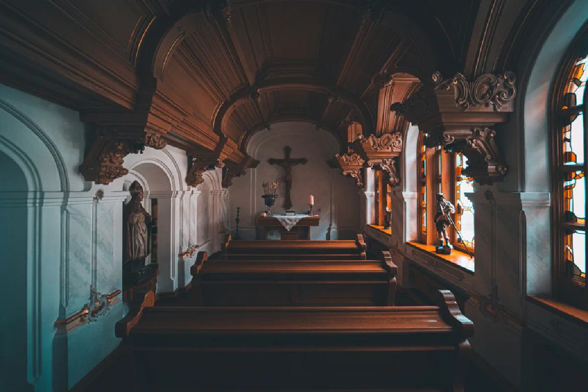 Serene church interior featuring ornate woodwork and wooden benches, showcasing traditional religious architecture.