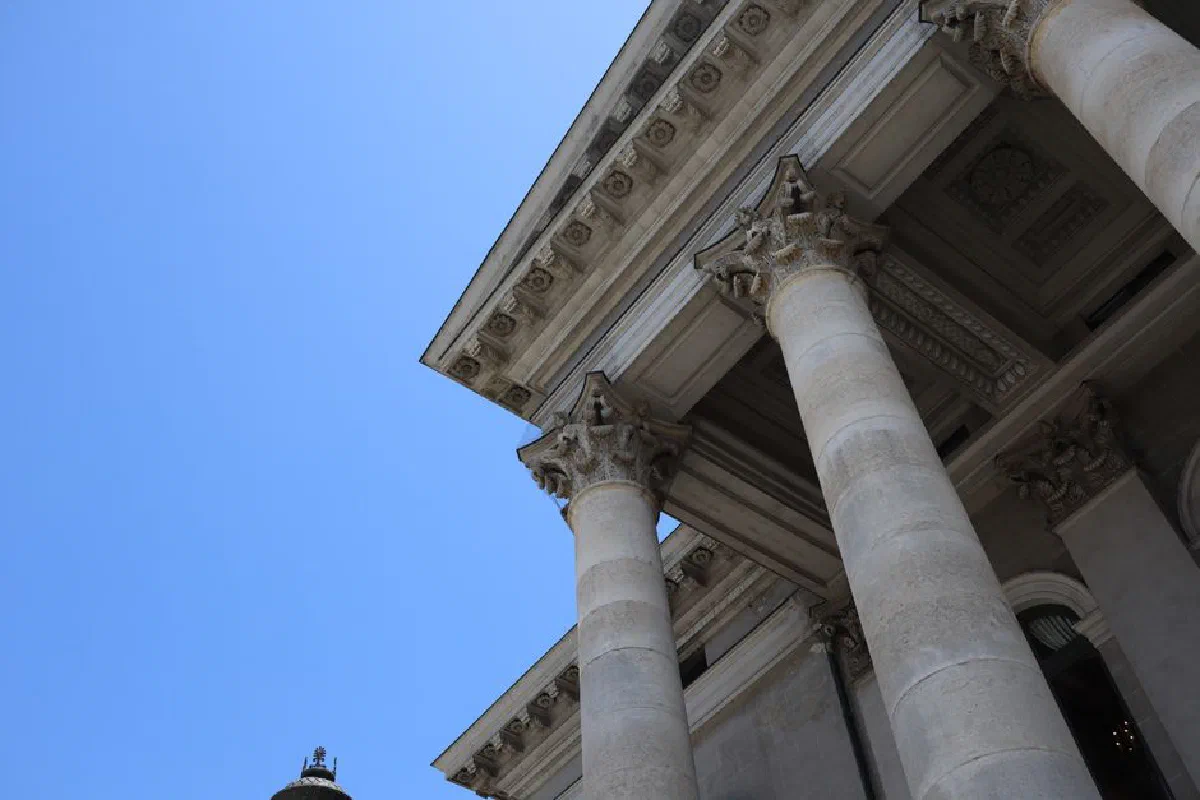 Low angle view of neoclassical columns in Munich, Germany against a clear blue sky.