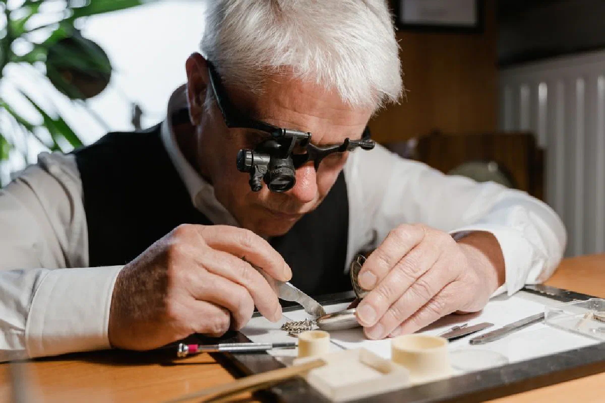A watchmaker meticulously repairing a pocket watch with precision tools and a magnifier.
