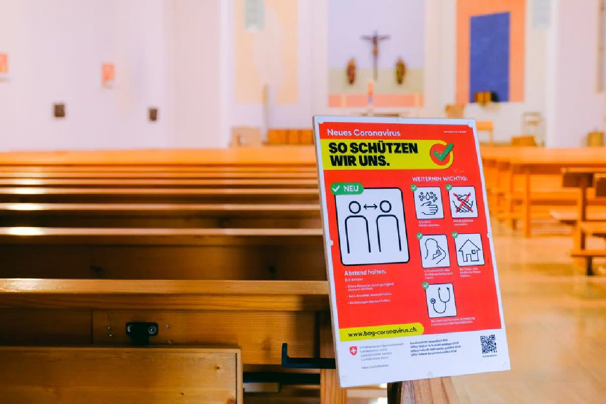 An empty church with Covid-19 safety sign emphasizing social distancing during pandemic.