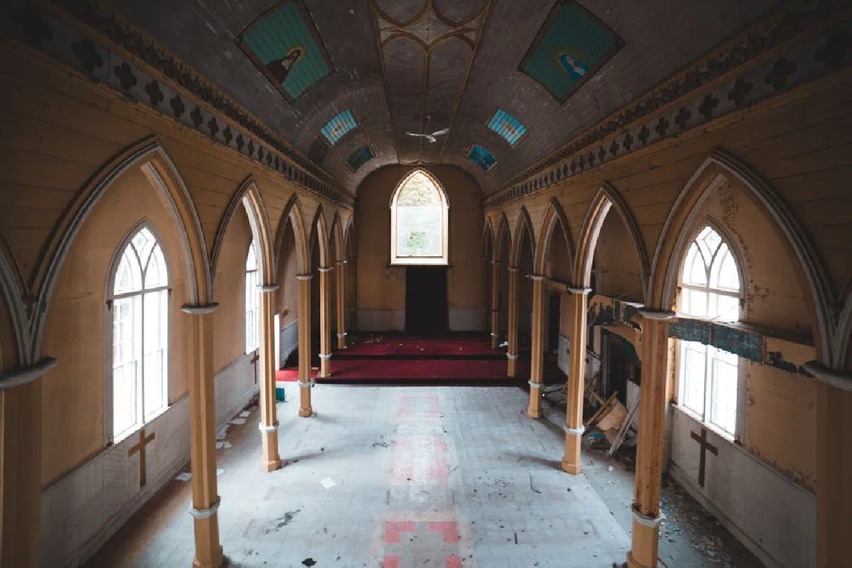 Bright hall in old abandoned catholic church including icons on ceiling and long wide windows composing with columns