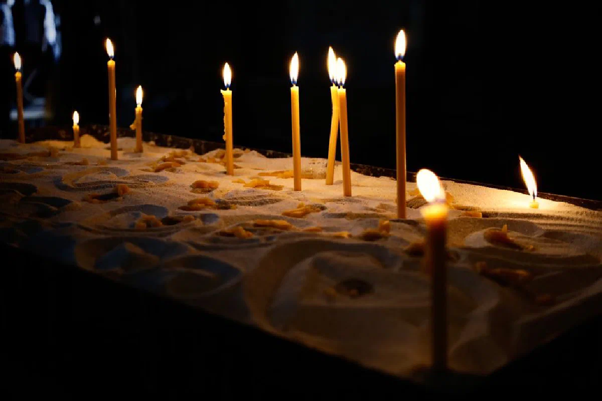 A serene display of burning candles casting warm light in a dark, spiritual setting.