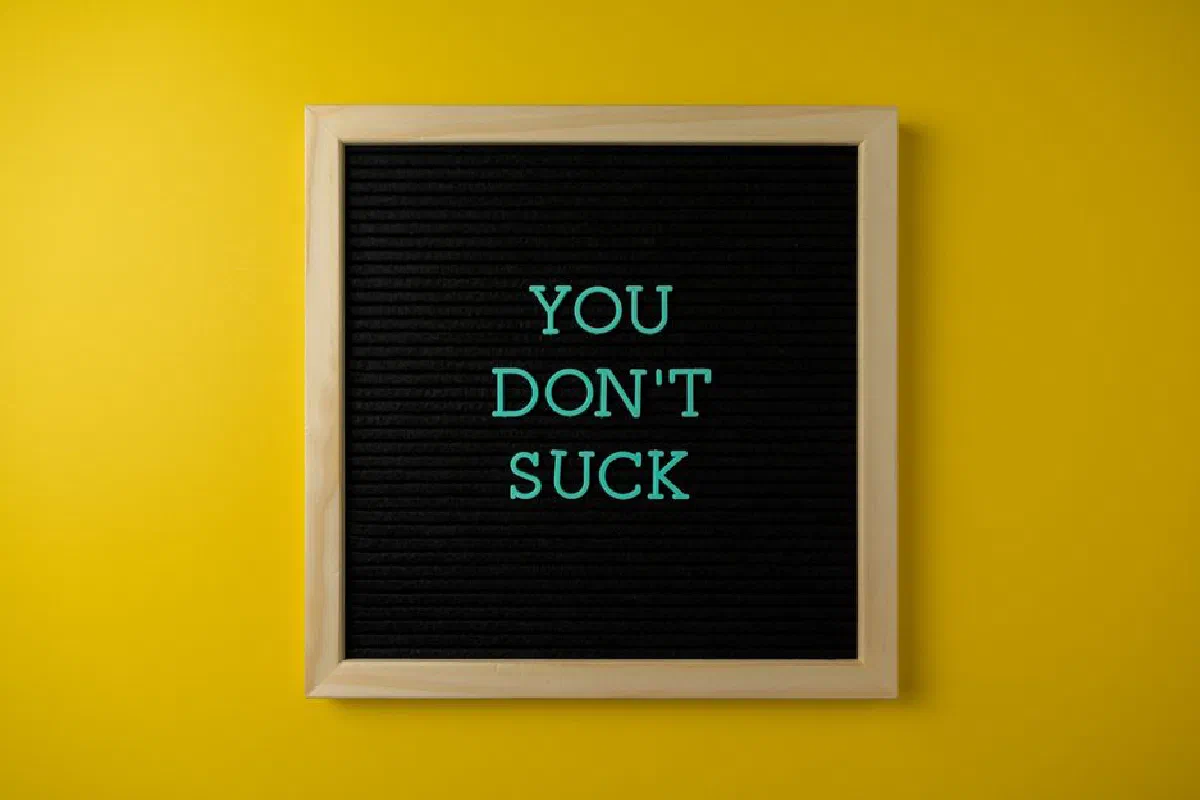Simple blackboard sign displaying an uplifting message against a vibrant yellow backdrop.