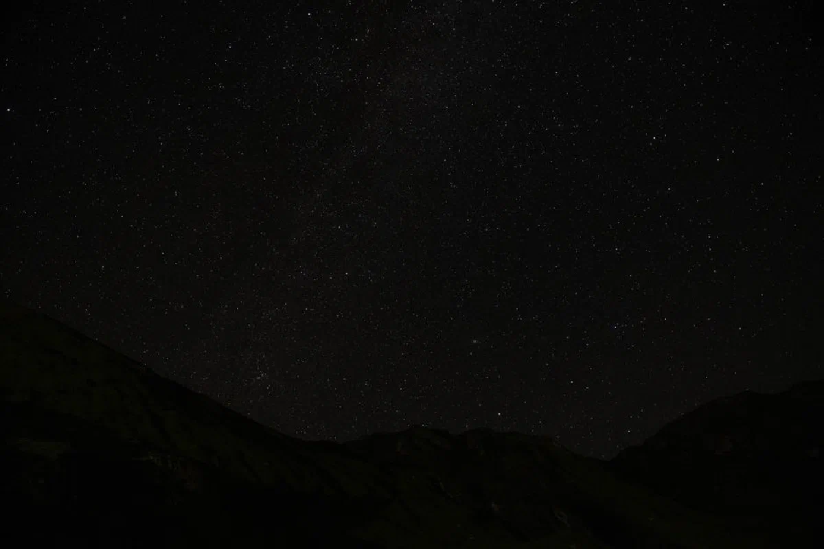 A captivating view of a starlit mountain night sky, showcasing countless stars.