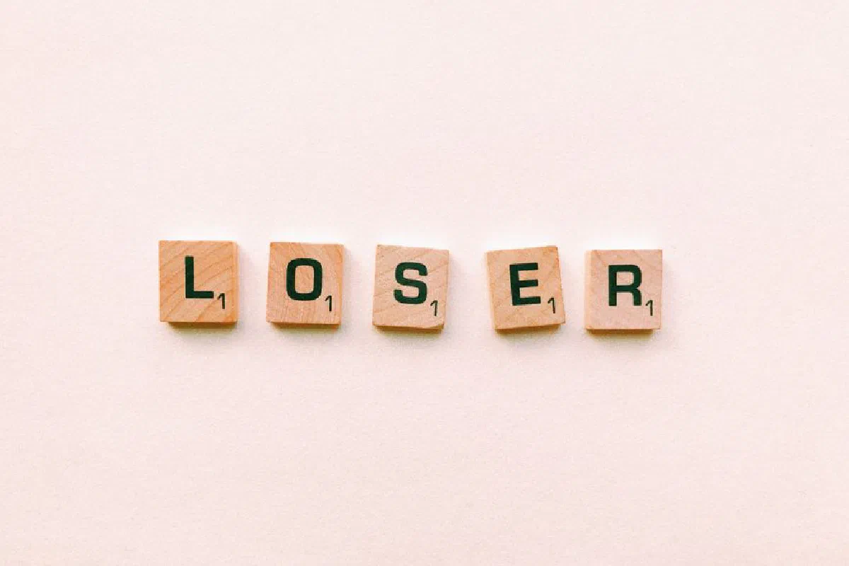 Five wooden tiles spell the word 'loser' in a minimalist and symbolic photo.