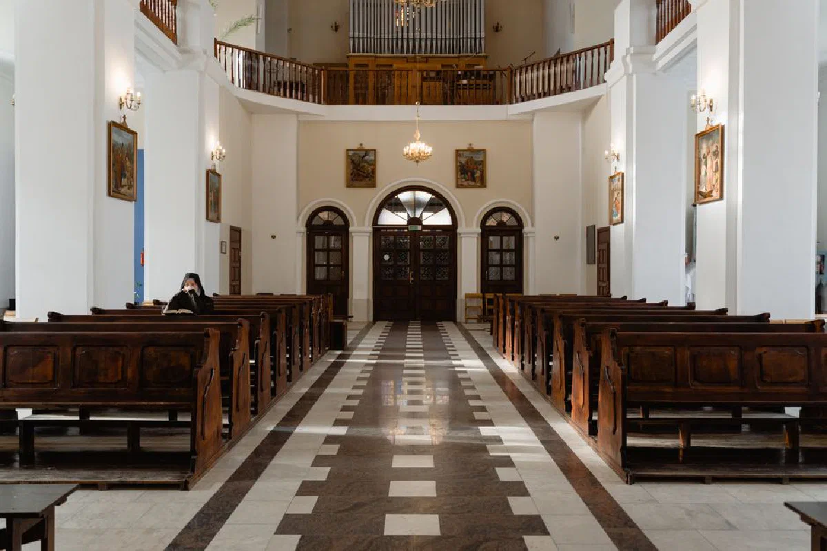 A serene view inside an empty church featuring classic wooden pews and religious decor.