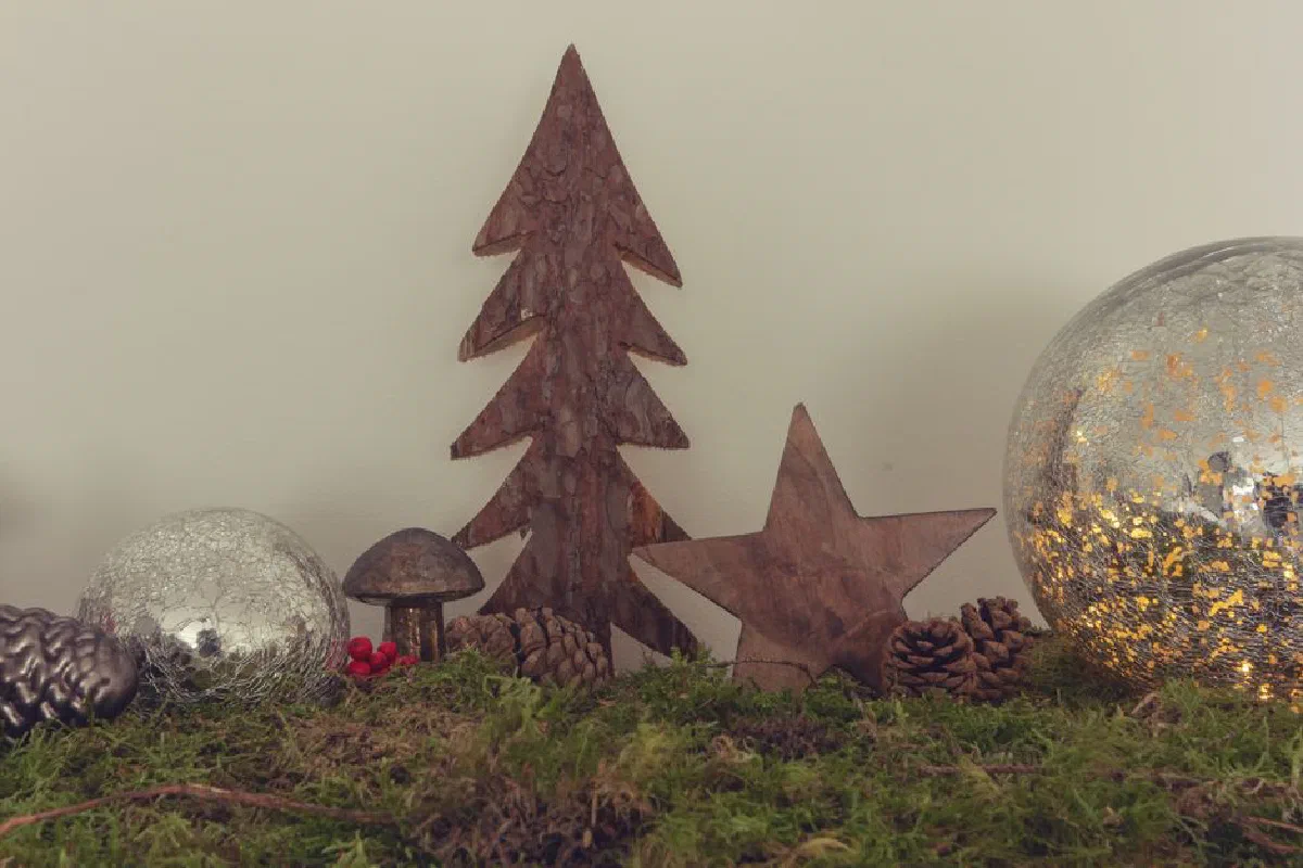 Festive rustic setup with wooden tree, star, and pine cones on moss. Ideal for cozy holiday themes.