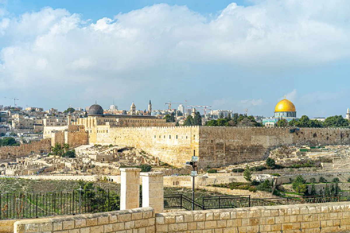Scenic view of Jerusalem's Old City featuring the Dome of the Rock and ancient walls under a blue sky.