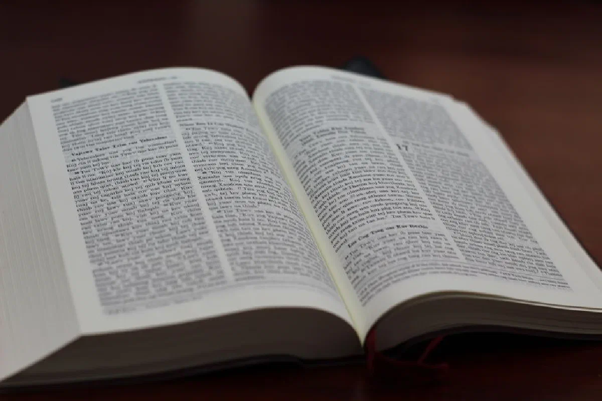 Close-up of an open Bible on a wooden table, showing text and details.
