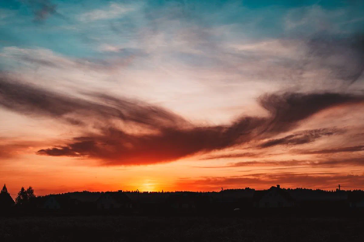Breathtaking sunset with dramatic clouds and vibrant colors over a rural landscape.