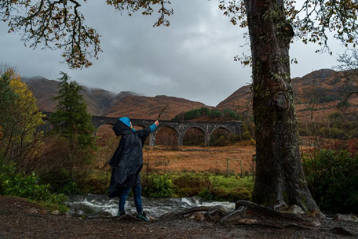 Person in raincoat near famous viaduct with scenic landscape view.