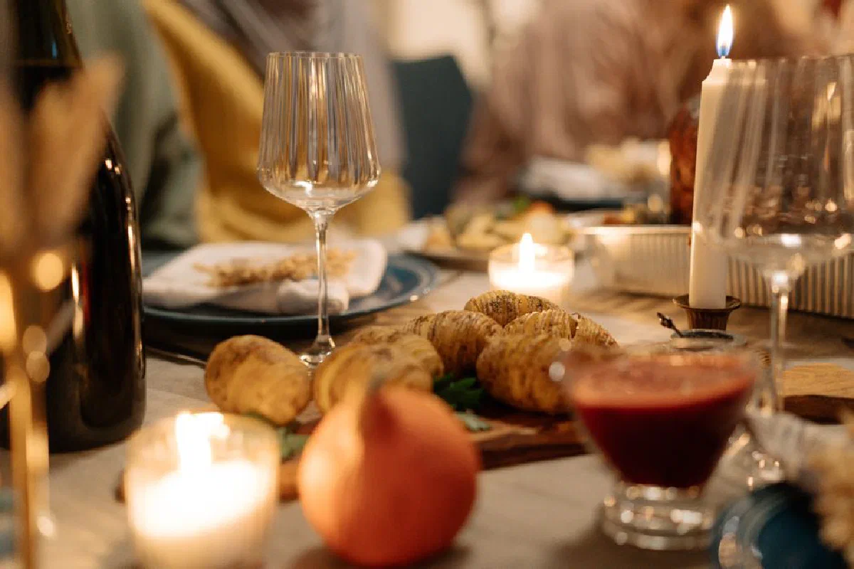 Warm, intimate dining table set with wine, candles, and Thanksgiving dishes.