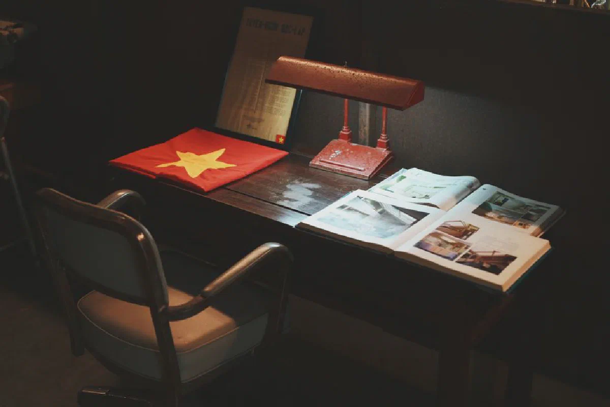 A rustic desk setup featuring a bright flag, vintage lamp, and open books, creating a nostalgic study atmosphere.