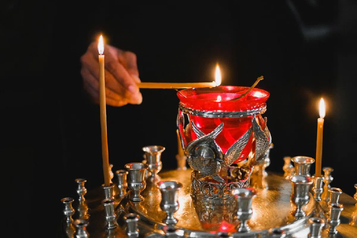 A serene candle lighting ceremony with a red glass lamp, reflecting spiritual traditions.