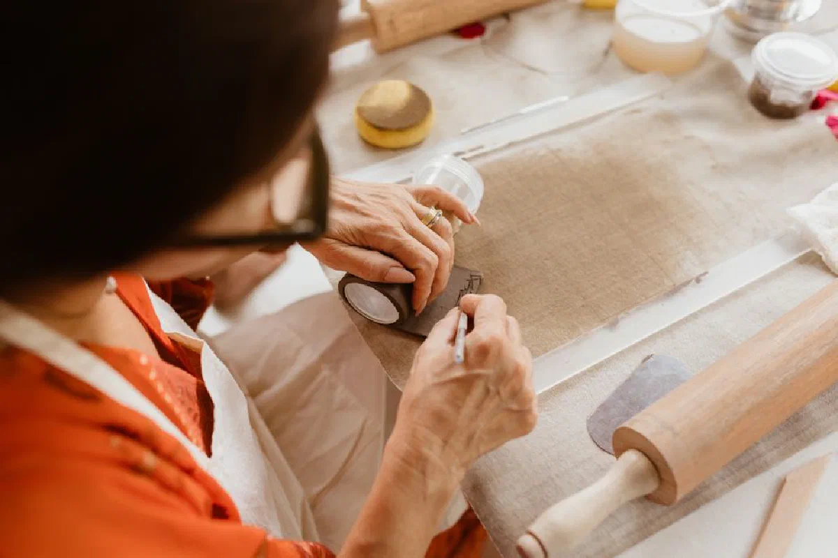 Woman crafting with precision, emphasizing traditional handmade techniques indoors.
