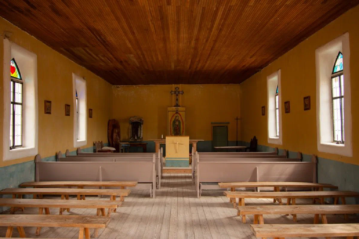 Interior view of a historic church in Terlingua, Texas, featuring wooden pews and religious altar.