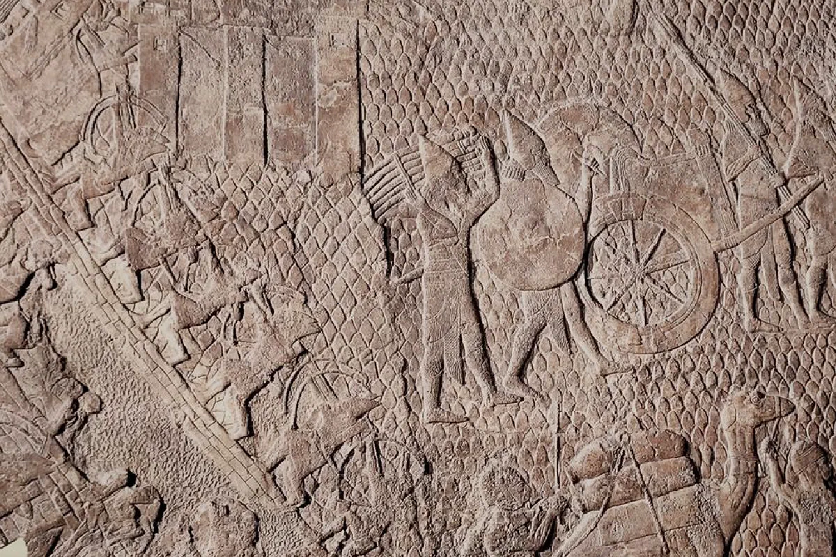 Detailed stone carving depicting an ancient battle scene with soldiers and chariots.