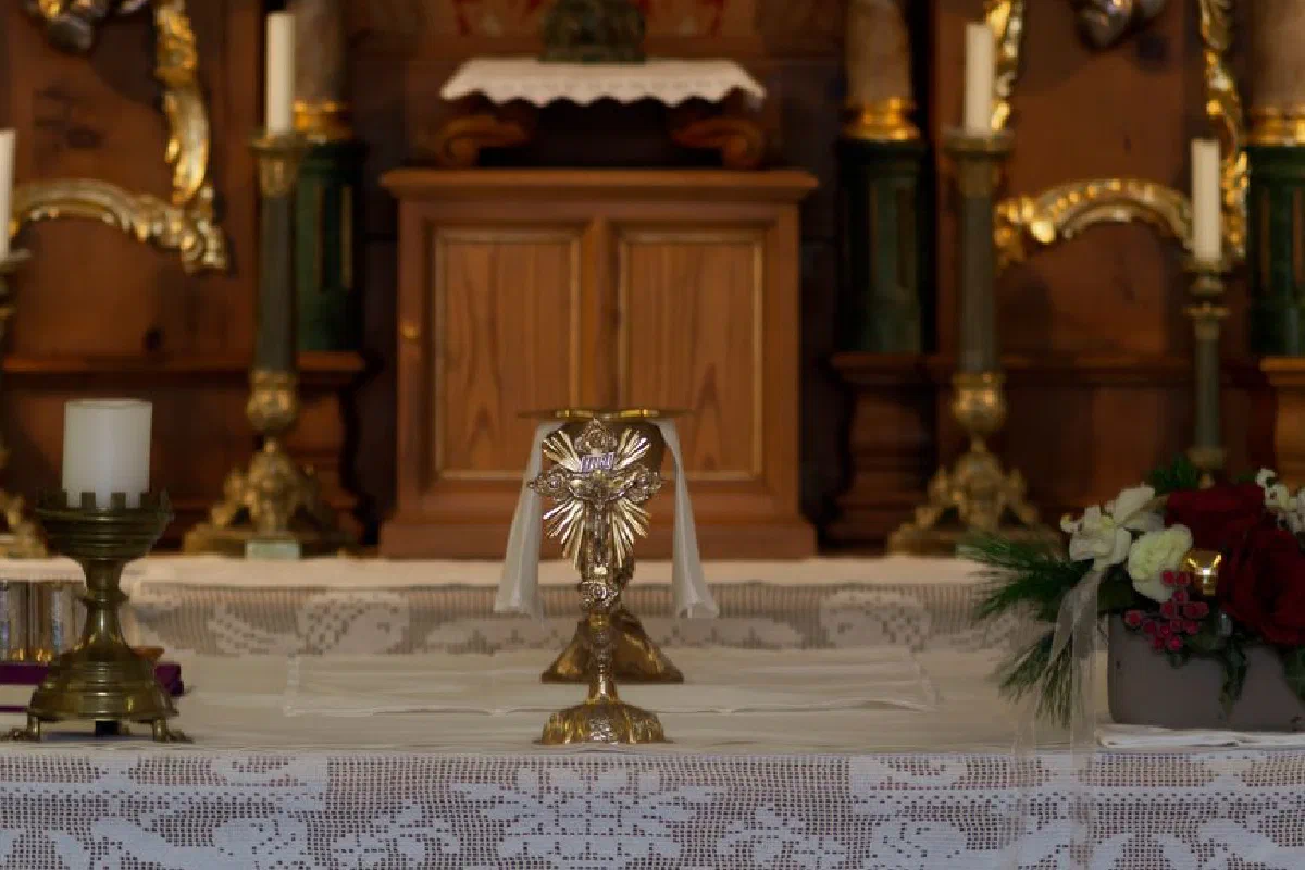 Close-up of a church altar featuring a chalice, candles, and floral decorations.
