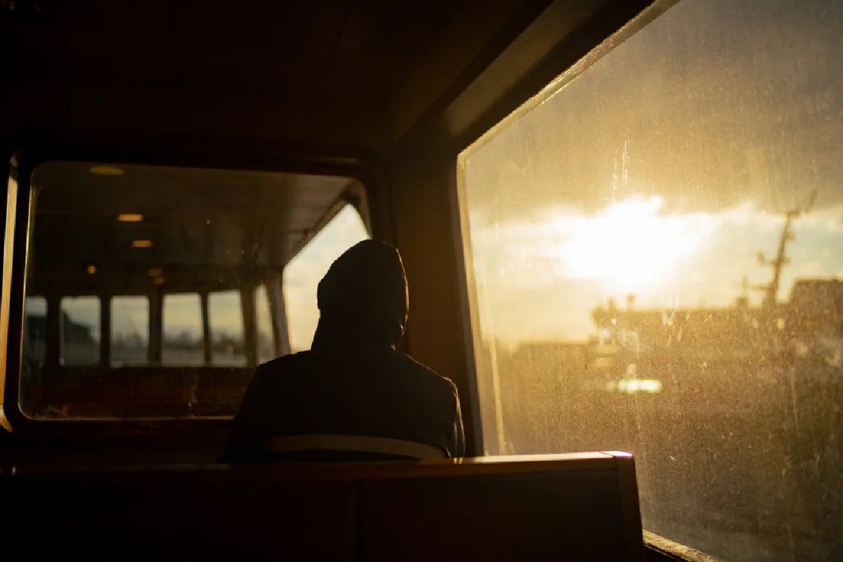 A person sits in silhouette on a ferry at sunset, gazing out at the serene horizon.