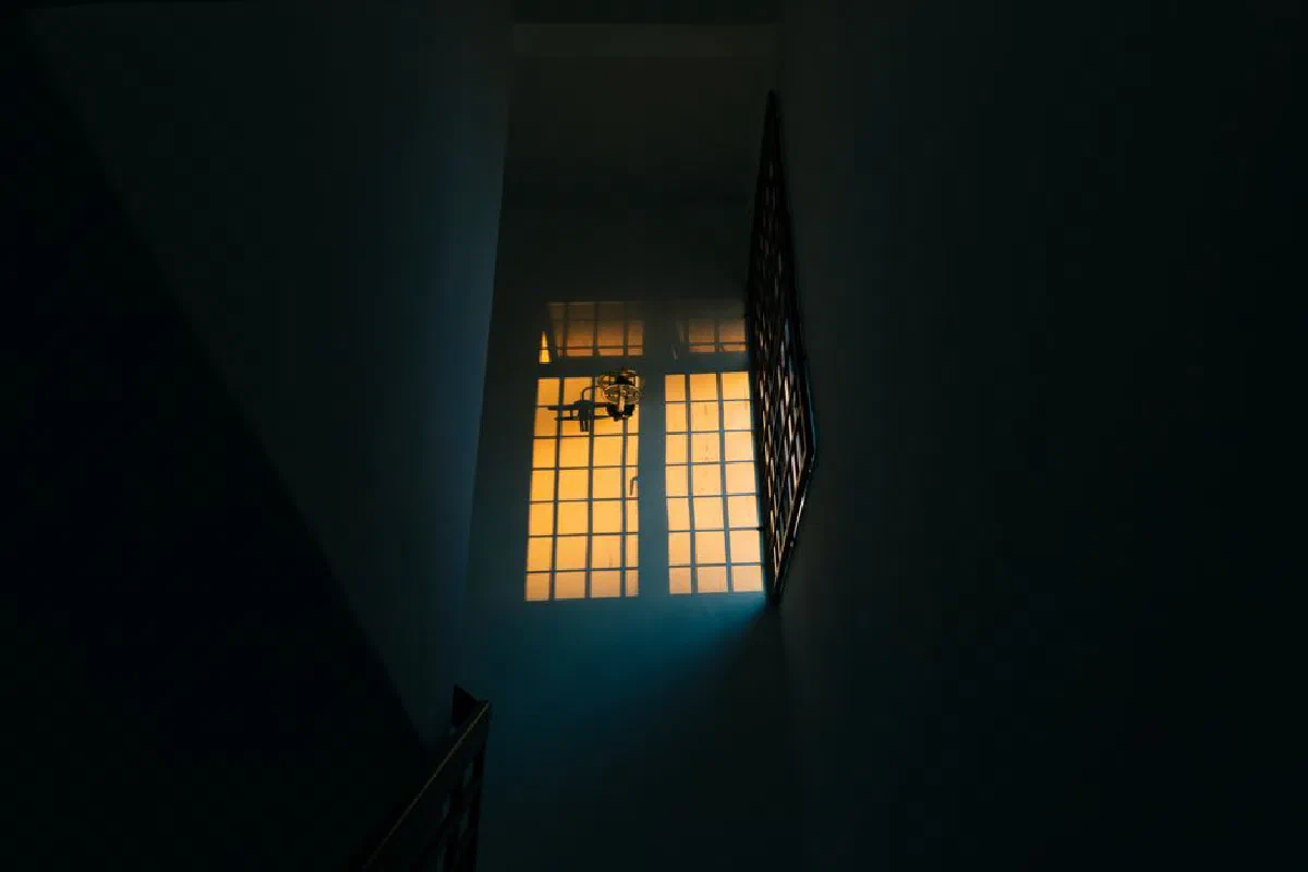 A dimly lit hallway with a warm glow from the window, creating a dramatic contrast.
