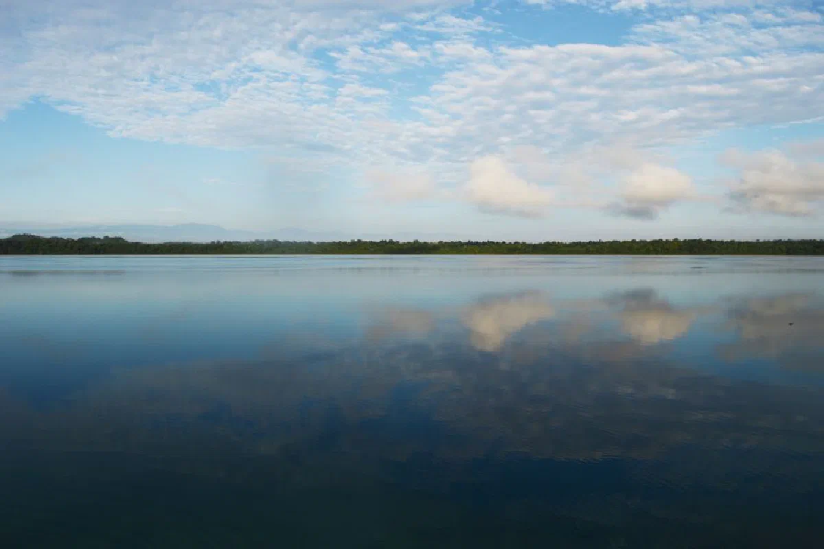 Tranquil scene of a lake with clear cloud reflections under a blue sky.