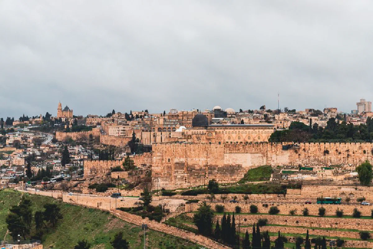 View of Jerusalem showcasing the ancient city walls and iconic architecture under a cloudy sky.