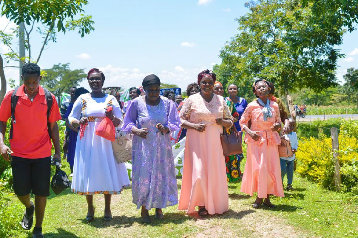 A joyful gathering of adults in colorful attire enjoying an outdoor celebration on a sunny day.