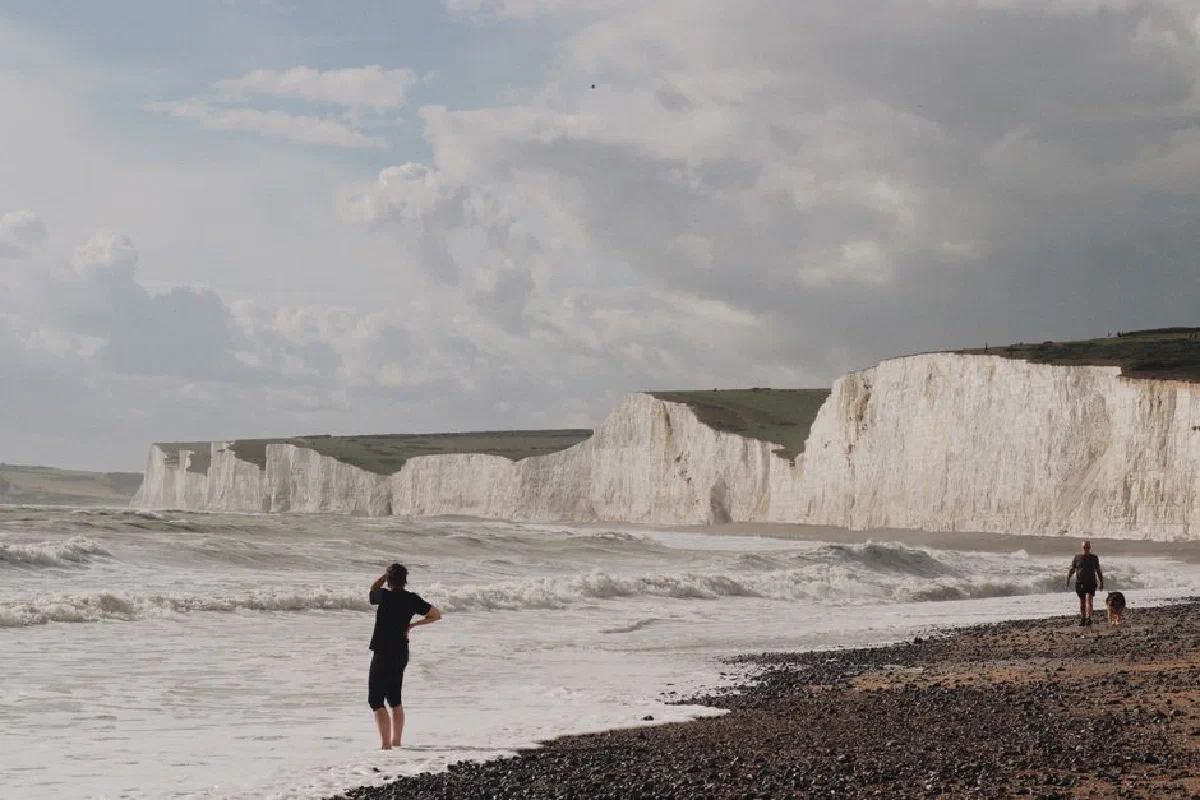 Scenic beach view of the Seven Sisters Cliffs, UK, with people enjoying seaside activities.