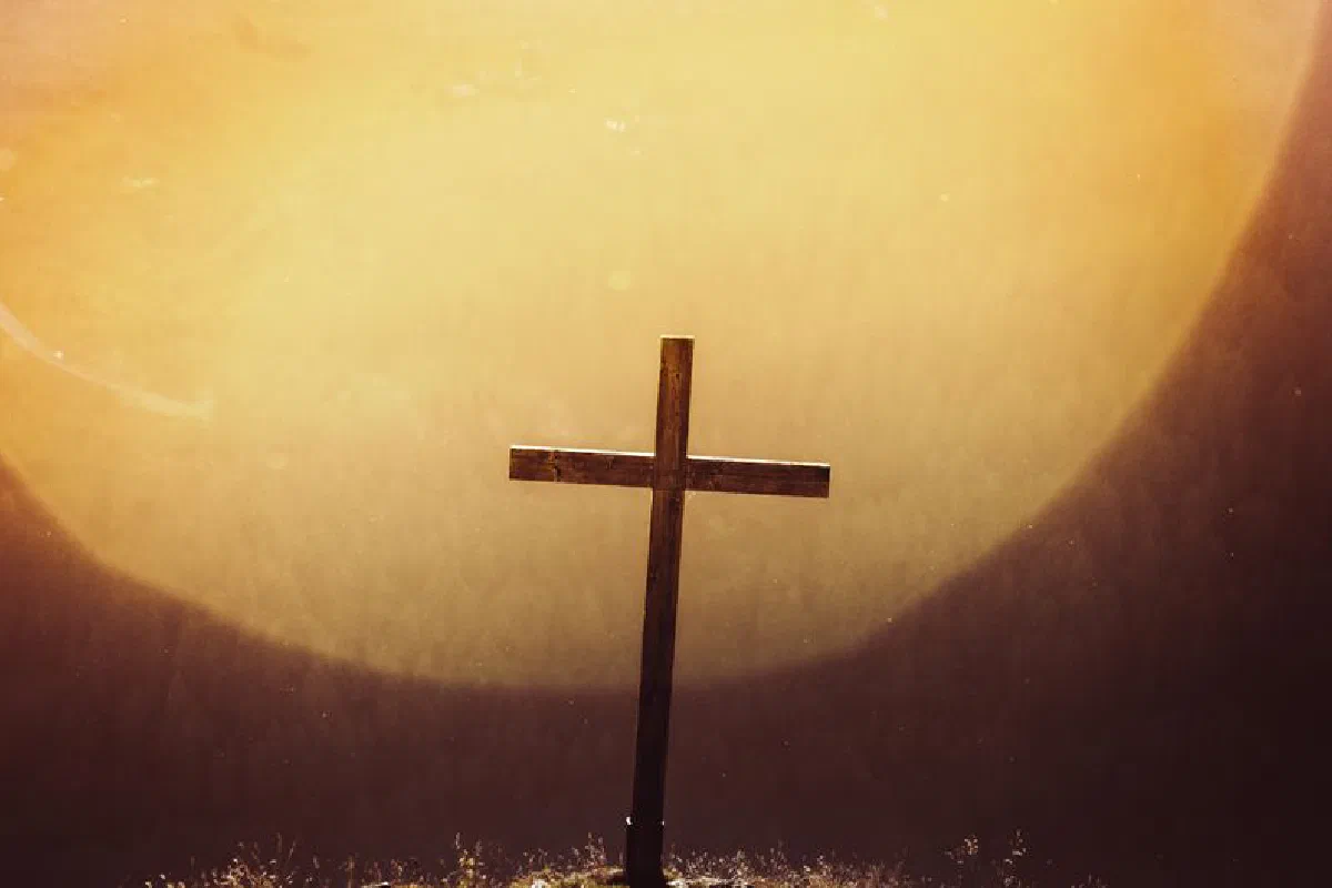 A striking silhouette of a wooden cross against a vivid sunset, evoking spirituality and peace.
