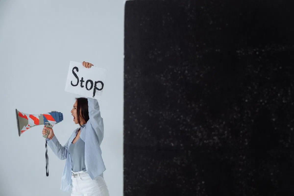 A woman holding a 'Stop' sign and megaphone in a protest, emphasis on activism and message conveyance.