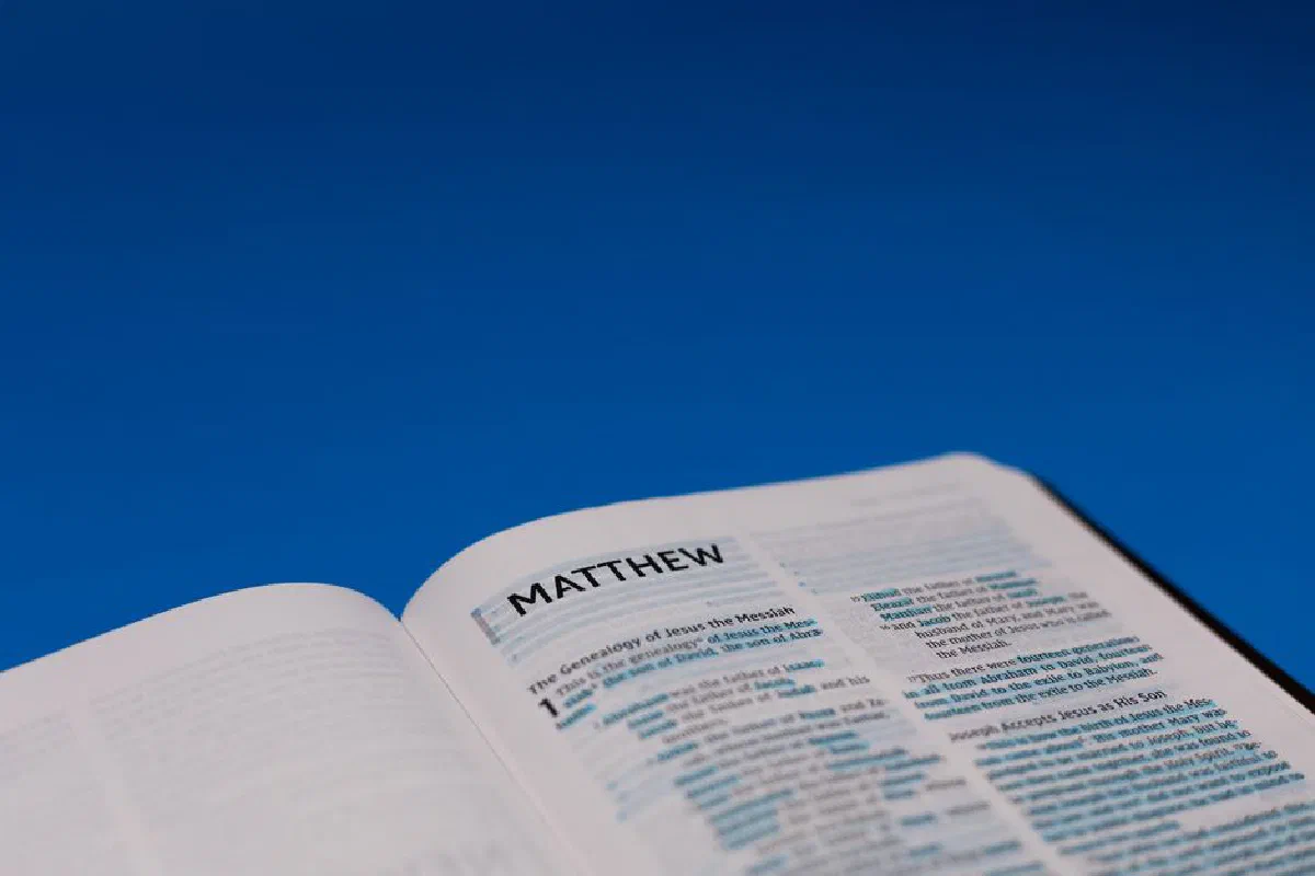 Open Bible displaying the Gospel of Matthew on a vibrant blue background.