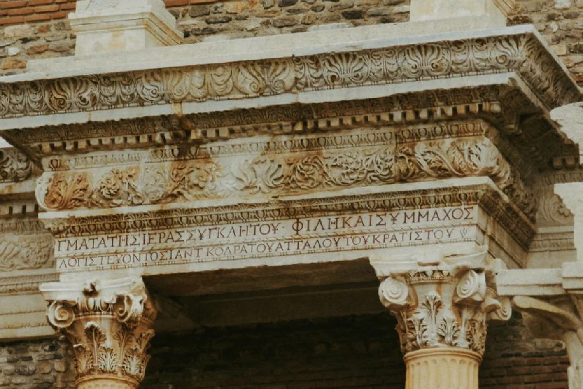 Intricate stone carvings on an ancient Greek temple facade with Greek inscriptions.