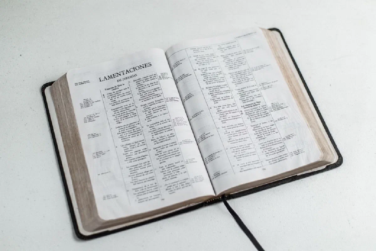 An open Bible displaying Lamentations, placed on a white surface.