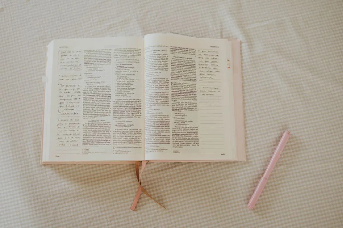 Open book with notes, pen, on gingham fabric, creating a cozy, contemplative setting.