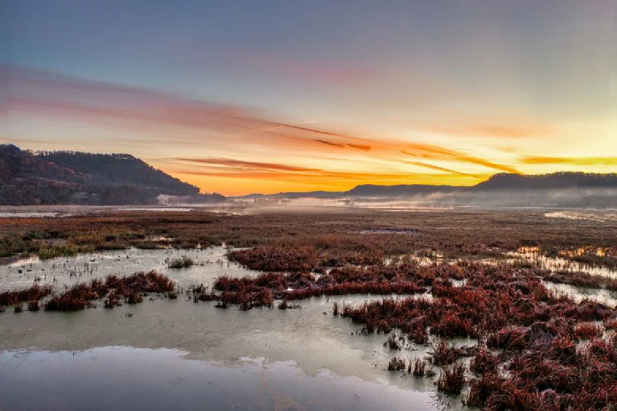 Scenic sunrise over the Mississippi River backwaters in Alma, Wisconsin, showcasing vibrant colors and natural beauty.