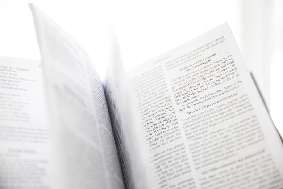 Close-up of an open book with visible text and turning pages in natural light.
