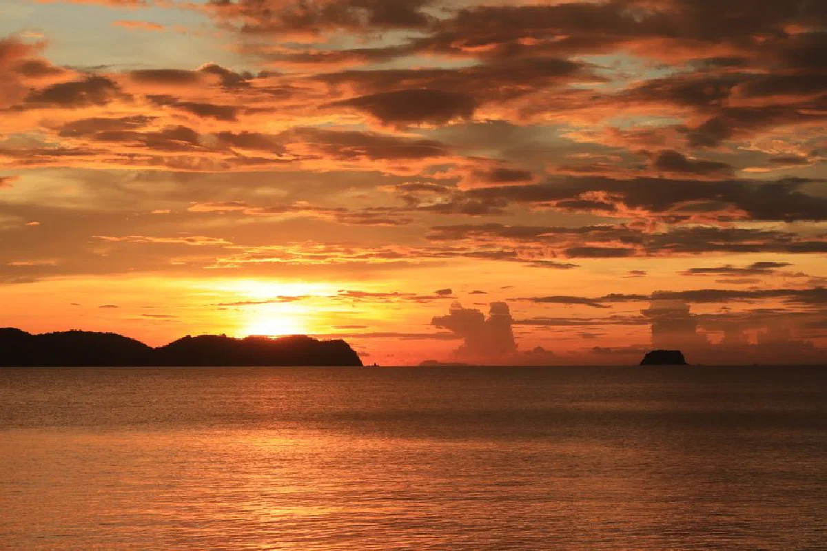Stunning sunset with vivid orange hues reflecting over calm ocean waters, capturing the beauty of nature.