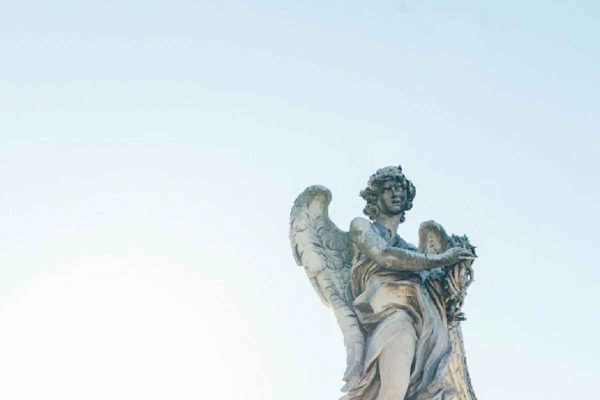 Marble angel statue set against the clear blue sky, capturing Rome's artistic heritage.