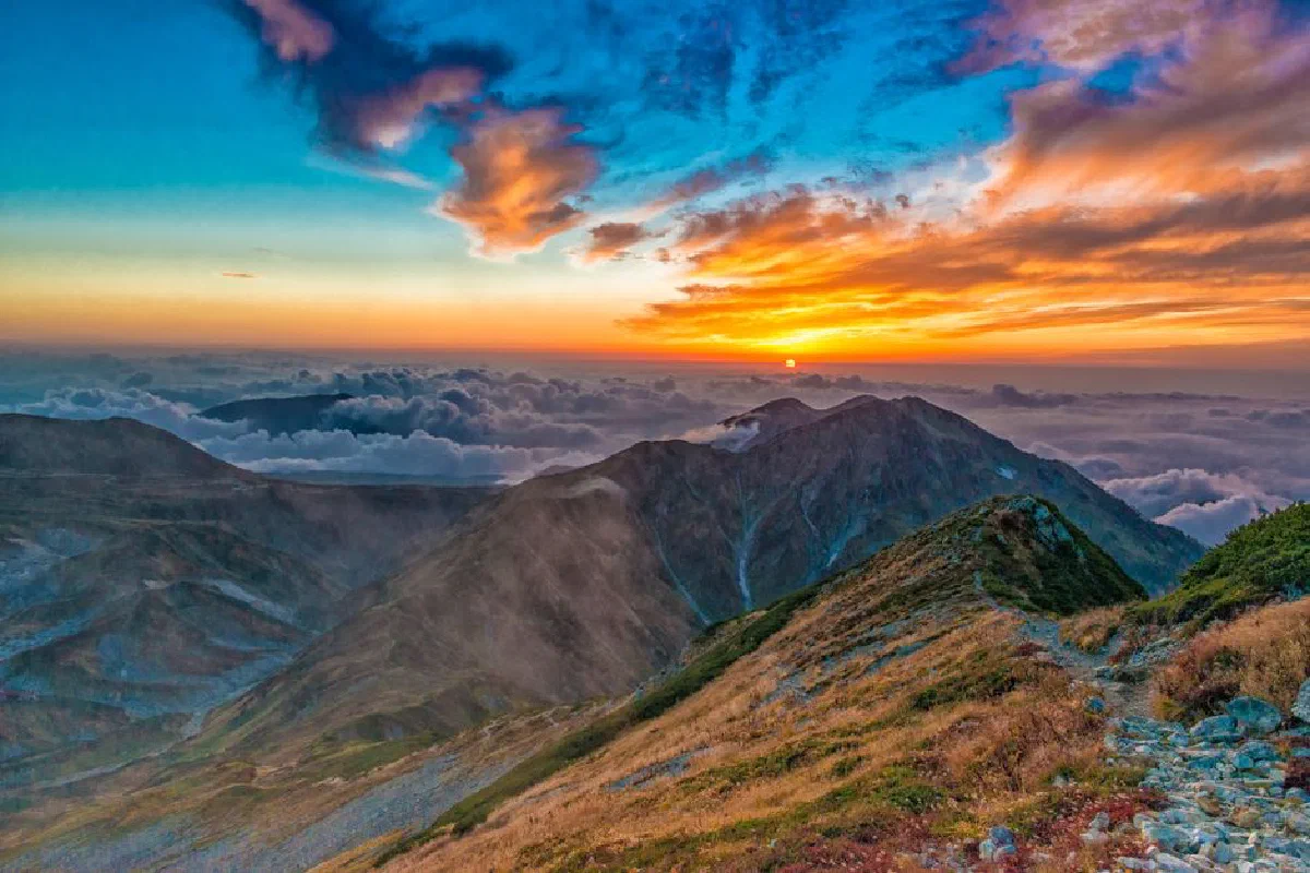 Breathtaking view of a mountain range and vibrant sunrise sky with clouds.
