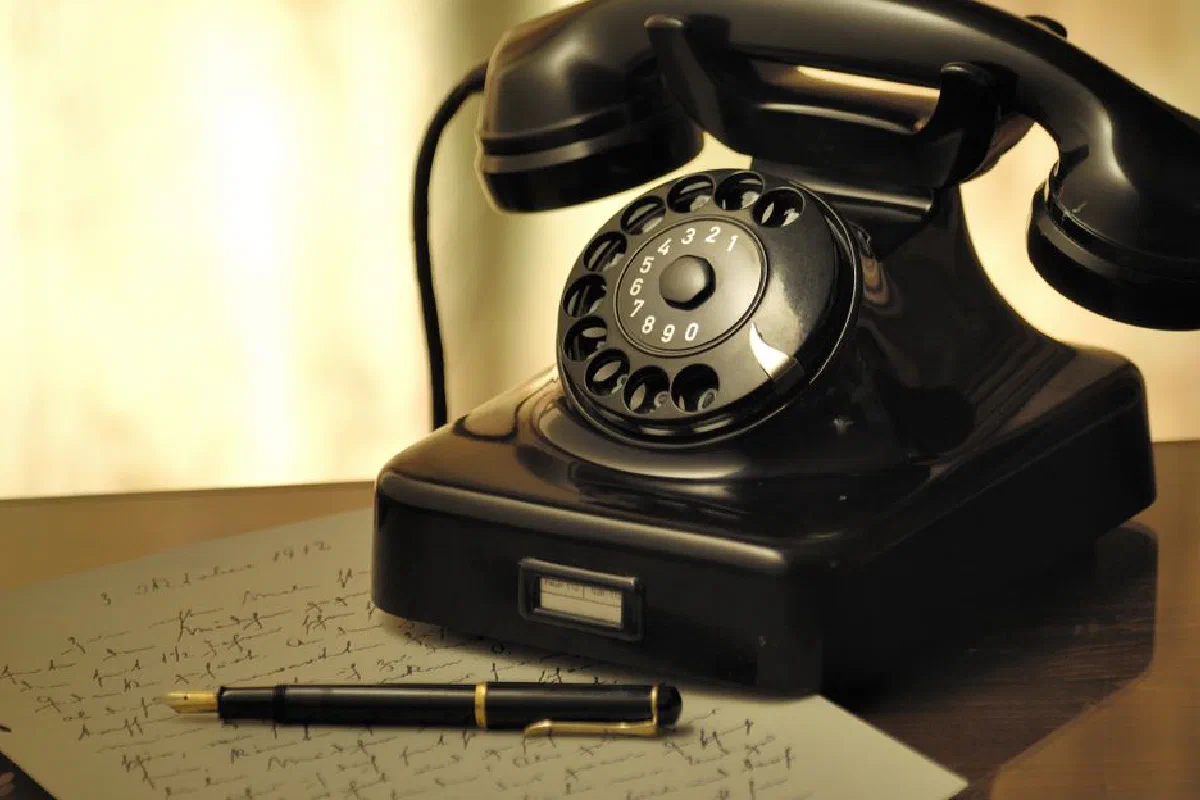 A nostalgic scene with an antique rotary phone and a fountain pen on a desk.