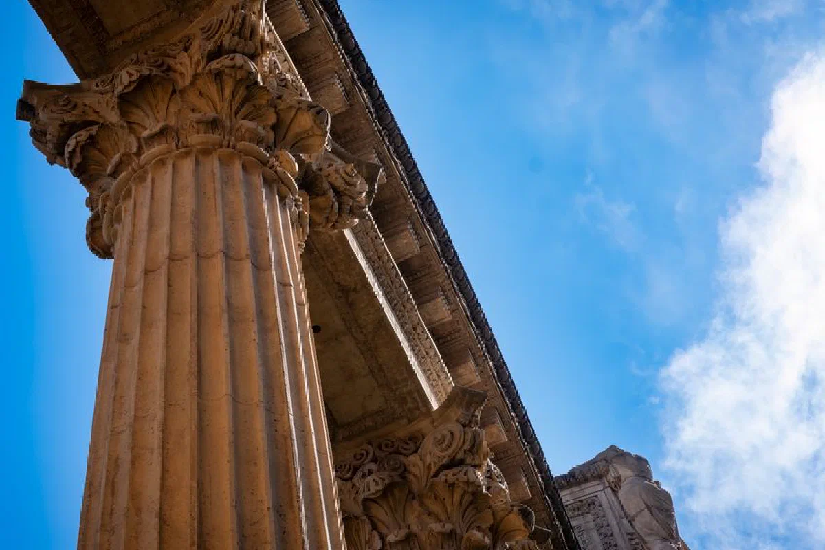 Close-up of ancient columns with intricate carvings under a clear blue sky.