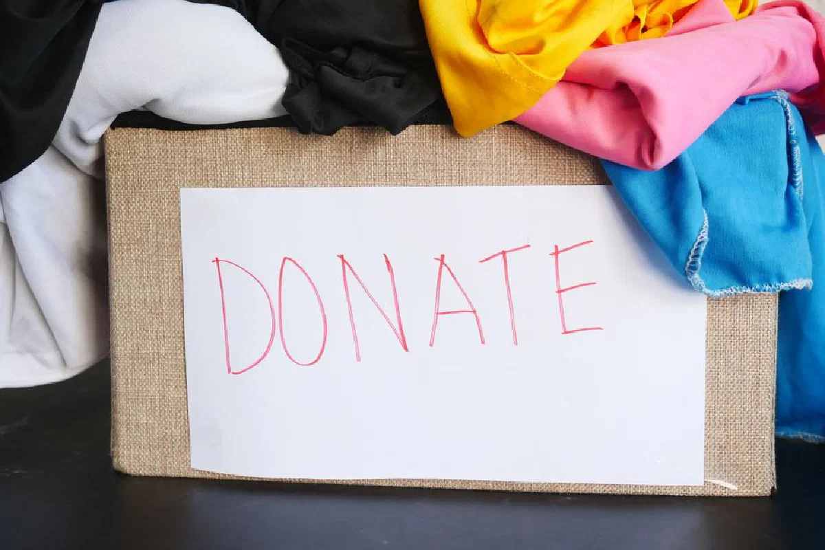 A donation box filled with colorful clothing, symbolizing charity and community support.