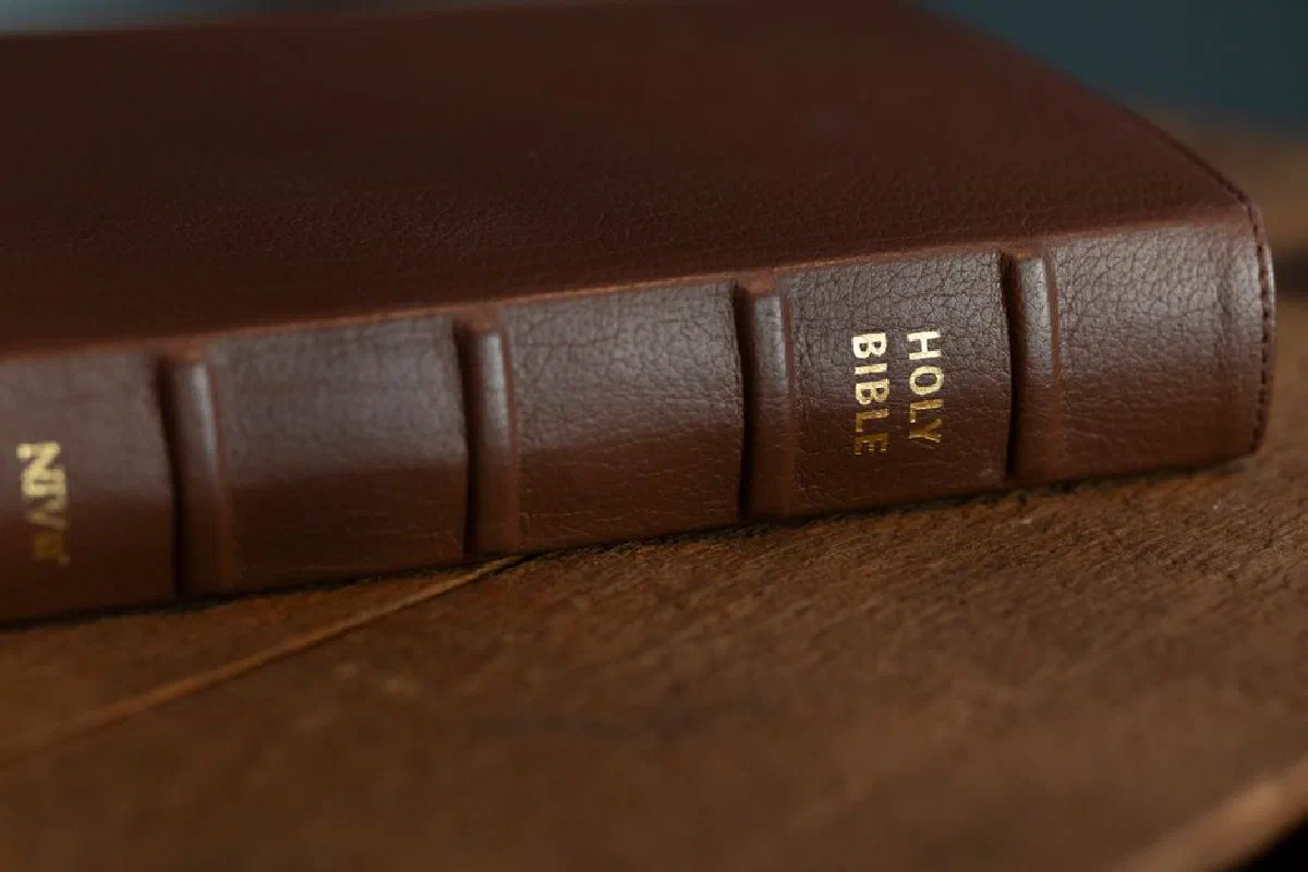 A close-up of a brown leather-bound Holy Bible resting on a wooden surface.