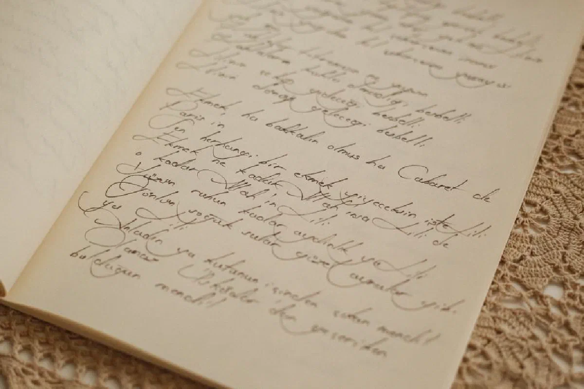 Close-up of a vintage journal with elegant cursive handwriting, placed on a lace tablecloth, embodying nostalgia.