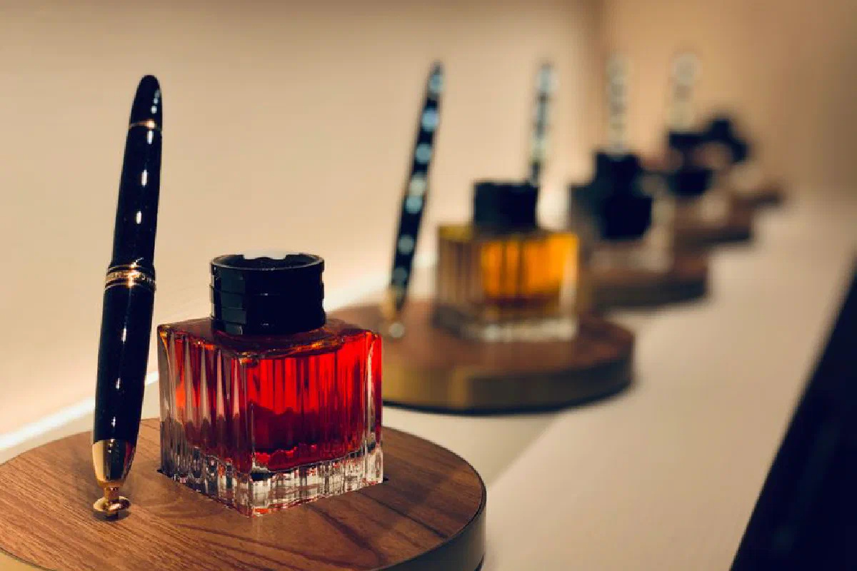 Close-up of vibrant ink vials with fountain pens on wooden stands. Creative and artistic display.