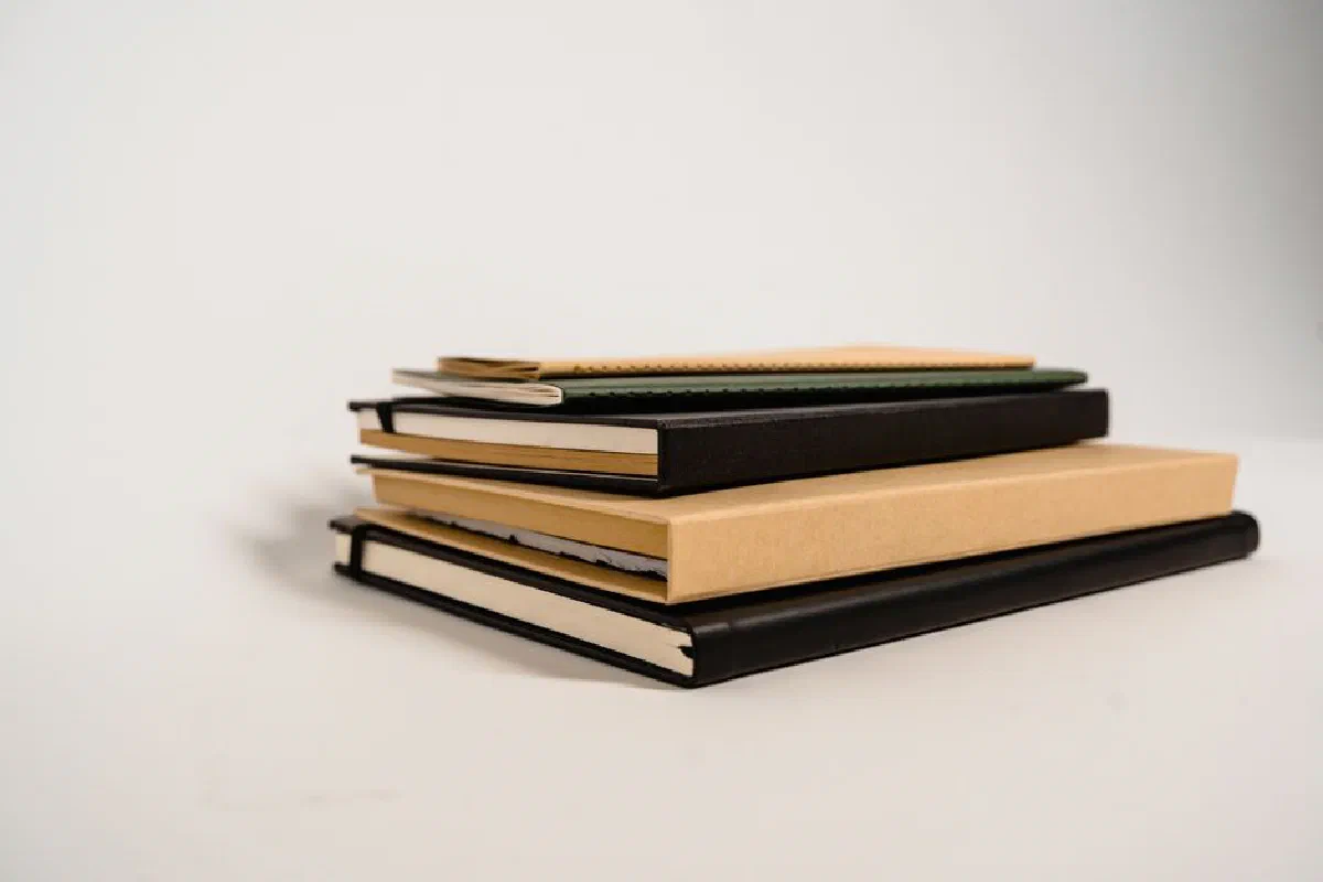 A stack of assorted notebooks with different colors and textures on a white background.