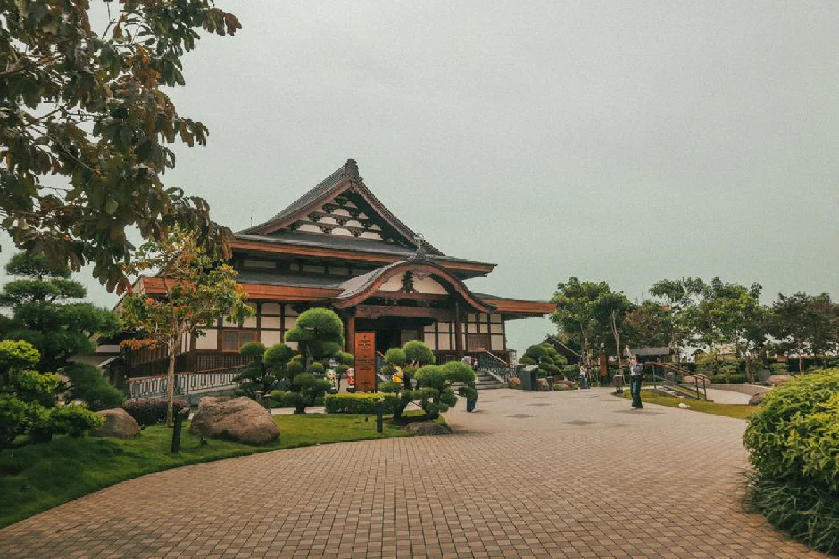 A serene traditional Japanese temple surrounded by lush gardens, captured on a cloudy day.