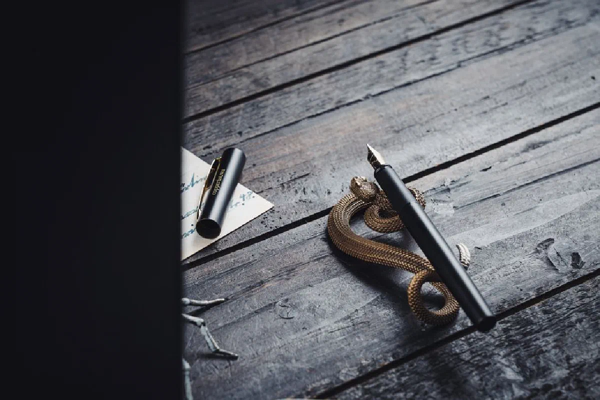 A vintage fountain pen elegantly displayed on a wooden desk with a decorative snake holder.
